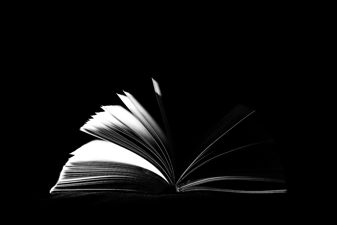 Dark image of an open book on a black background