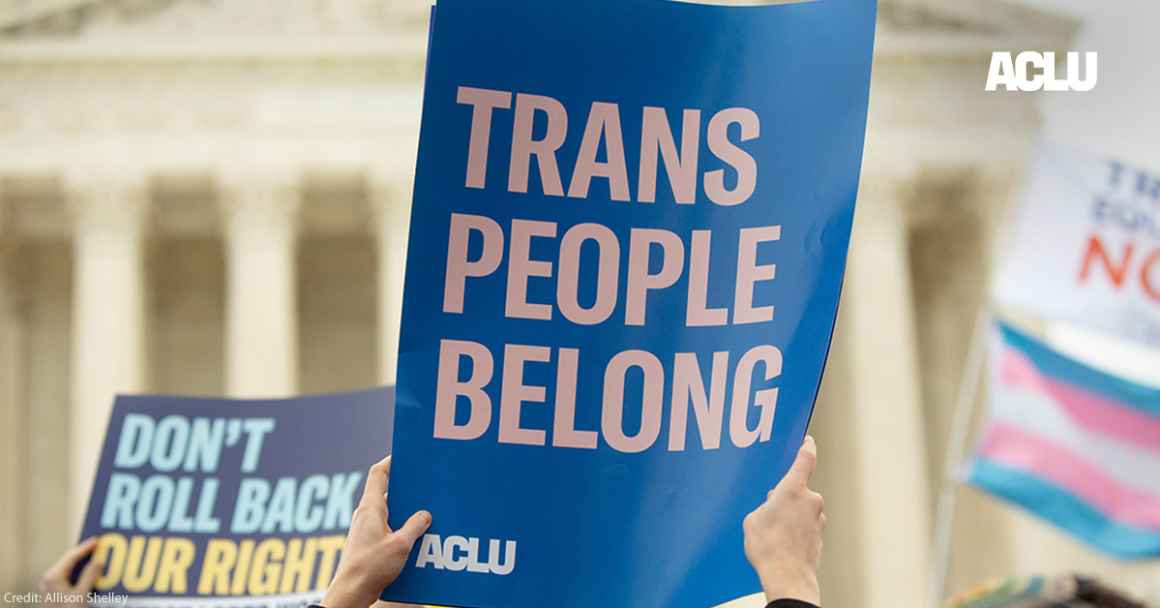 The words "trans people belong" on a blue poster in front of the U.S. Supreme Court building 